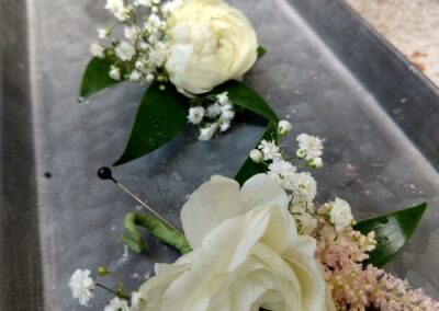 Metal tray with white boutonnieres and corsages displayed