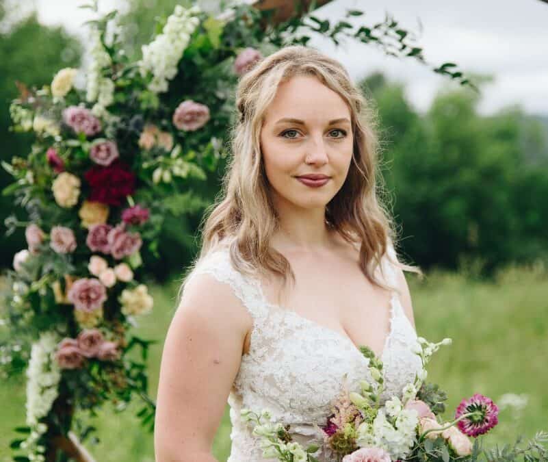 bride standing before hexagon arch with bouquet of flowers