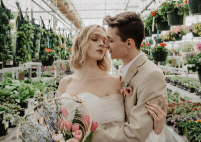 bride and groom standing in a greenhouse holding a bridal bouquet