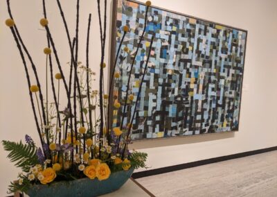 Yellow and blue floral arrangement in front of painting