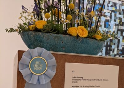 Yellow and blue floral arrangement with best creative design award ribbon